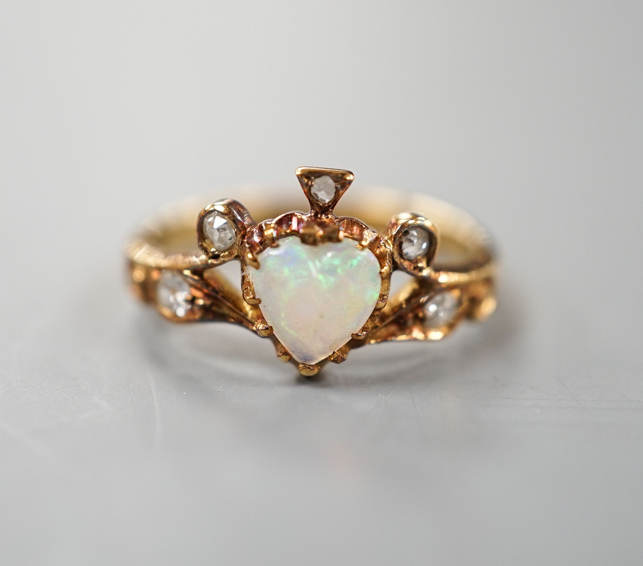 A late Victorian 18ct gold, heart shaped white opal and five stone diamond chip set dress ring, size I, gross weight 2.6 grams.